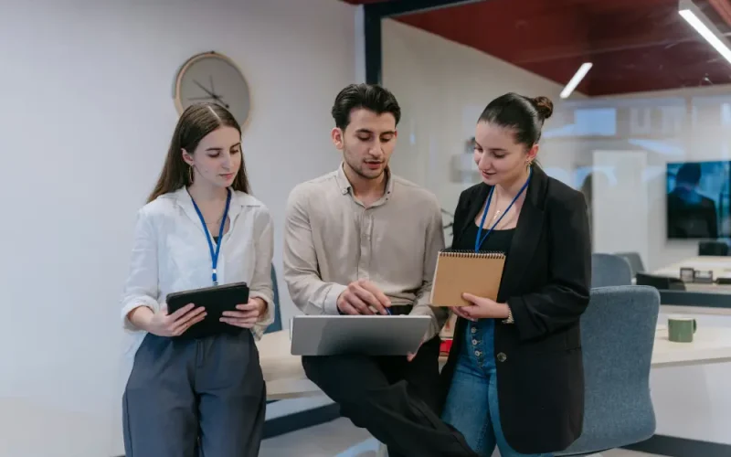 Three young professionals in an office setting collaborating on a project