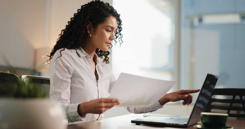 A focused businesswoman with curly hair sits at a desk