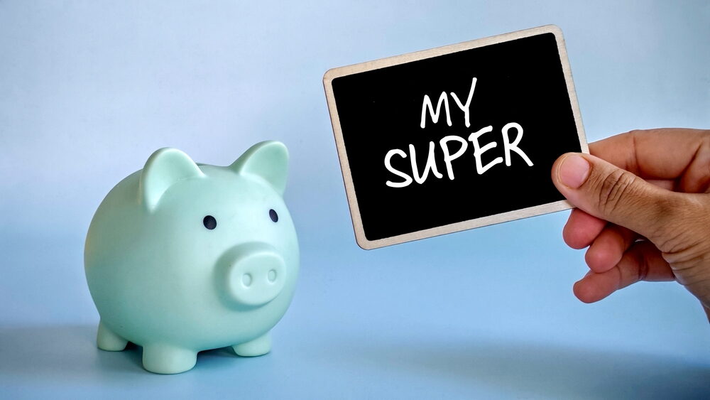 A light green piggy bank sits next to a hand holding a small blackboard that says "MY SUPER," representing retirement savings